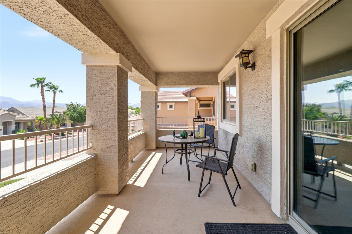 Covered balcony with table seating, neighborhood views, and space to enjoy coffee or fresh air.