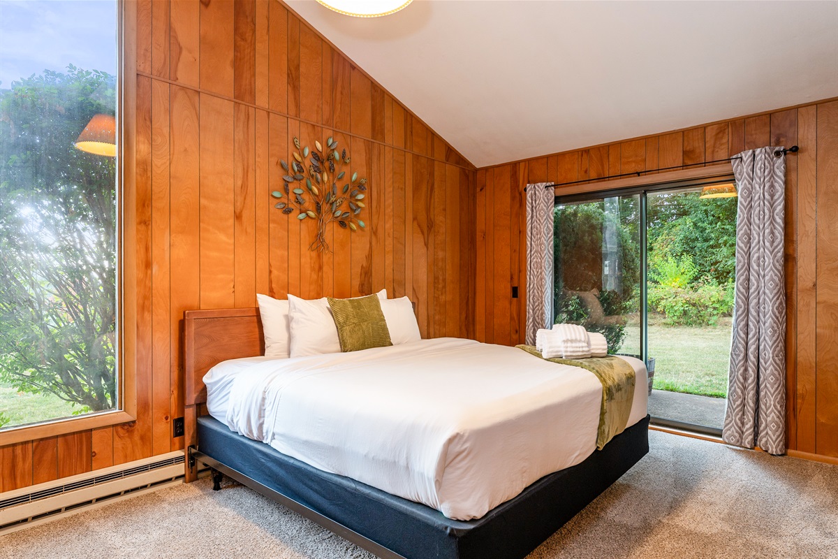 Bright bedroom with large windows and sliding doors to the yard, offering comfort and natural light.