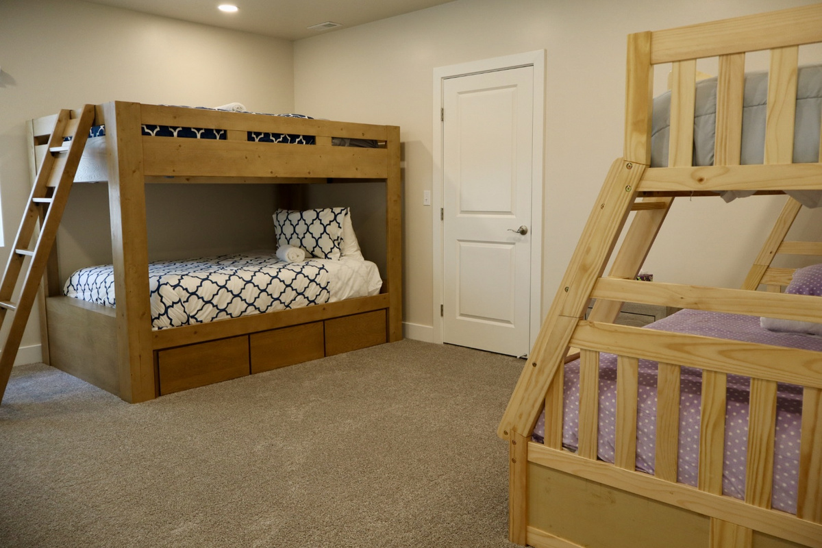 The fifth bedroom is perfect for kids or extra guests, featuring a sturdy bunk beds with two full-size mattresses, recessed lighting, and a large window that fills the space with natural light. There is a second twin over a full  bed in this room also