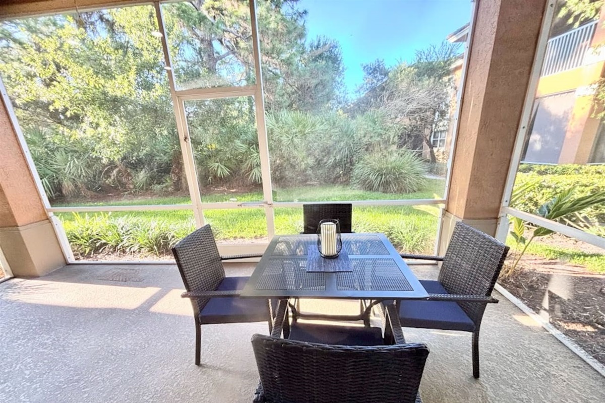 Private screened patio with outdoor dining space and peaceful garden views — perfect for enjoying morning coffee or relaxing outdoors.