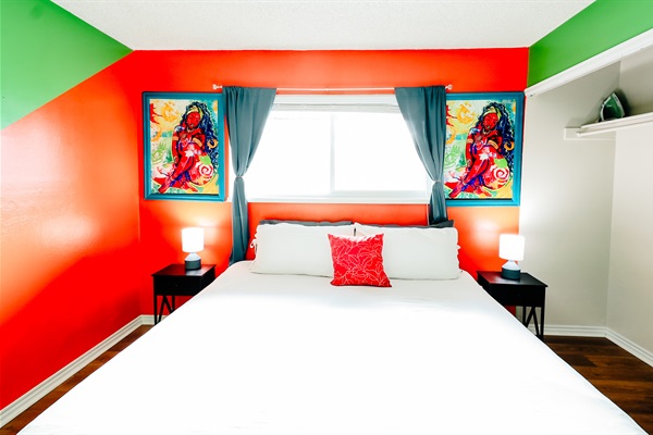 Modern Oasis: King Bed in Crisp White with a Hint of Orange, Set against Bluish-Green Curtains and Harmonious Green-and-Orange Walls. Natural Light and Entertainment Await 🍊🌿📺