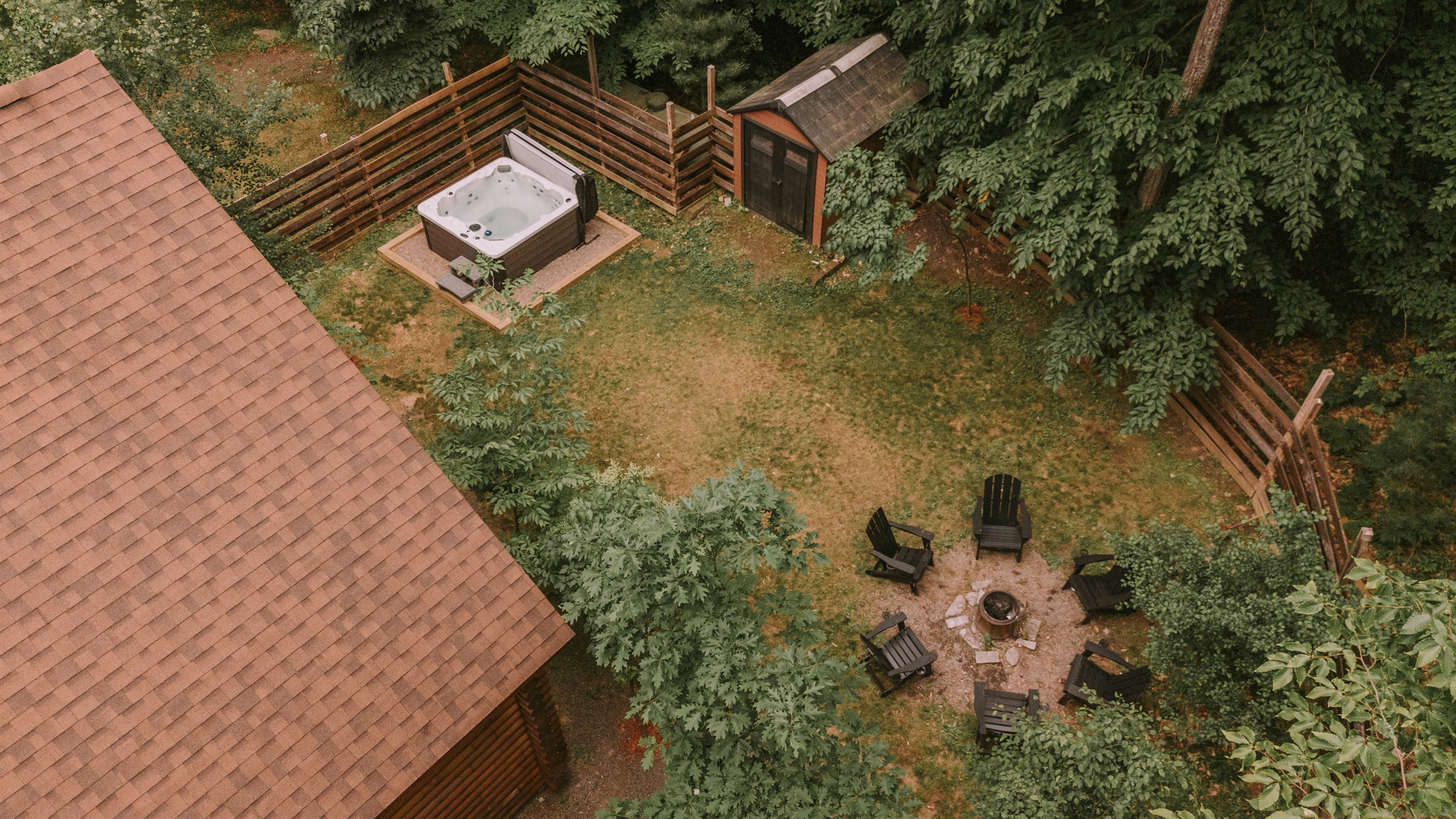 Aerial view of fenced yard, hot tub and firepit.