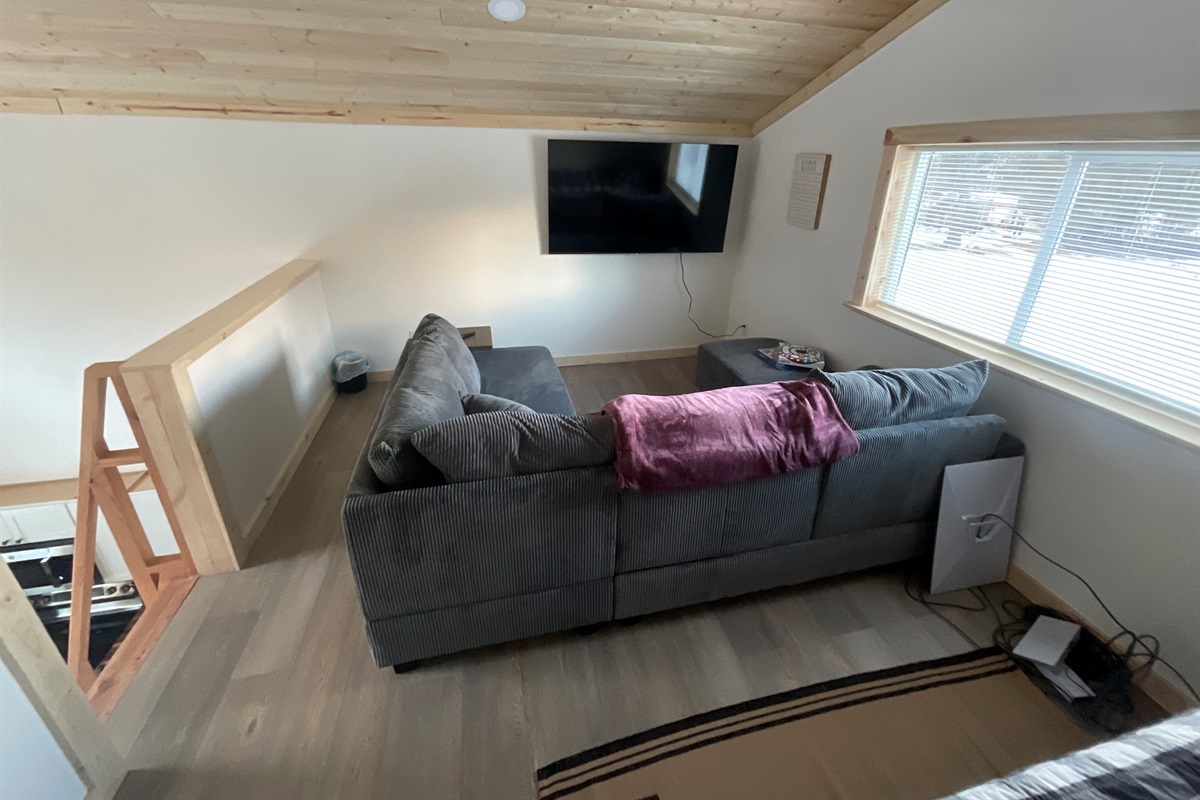 Loft living area - sectional sofa and big screen TV. [Photo is representative but may not be from this cabin]