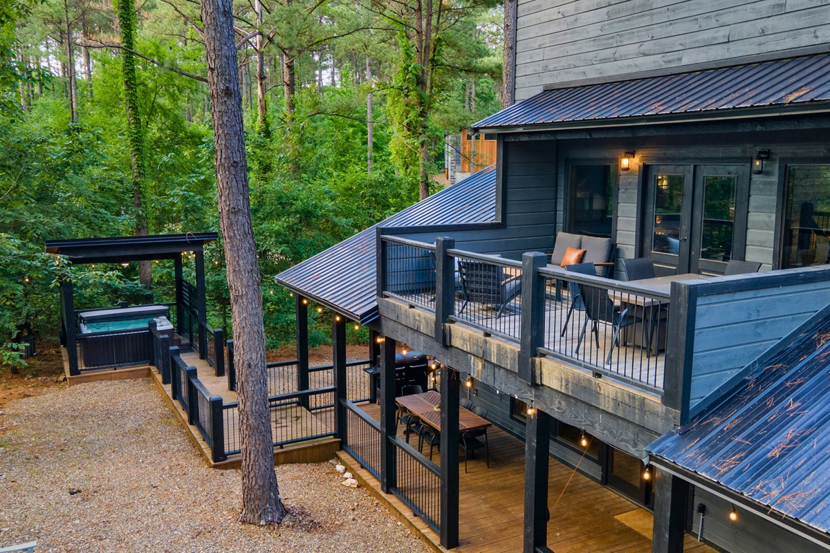This cabin's multi-level decks offer various outdoor experiences, from the cozy lounge area to the dining space below, all surrounded by the tranquility of tall pines.