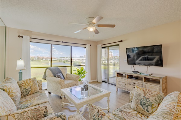 Smart TV in the living area with balcony access and golf course view