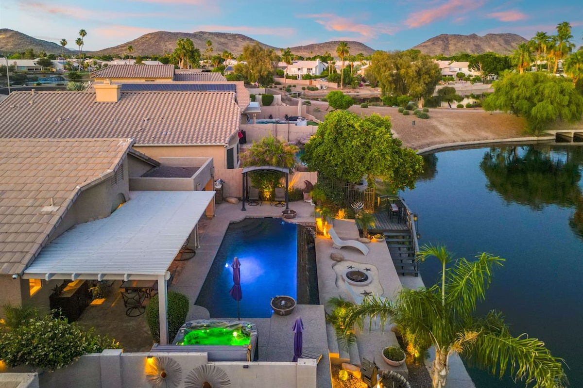 The pool glows after dark while the hot tub steams and the lake shimmers just beyond the yard — this is what Arizona evenings were made for.