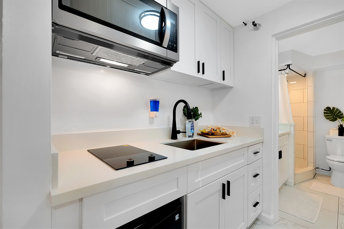 Your modern Waikīkī escape begins here — a bright, fully equipped kitchenette featuring sleek countertops, soft lighting, and easy access to the bathroom for total convenience. Designed for guests who appreciate comfort, function, and island elegance.