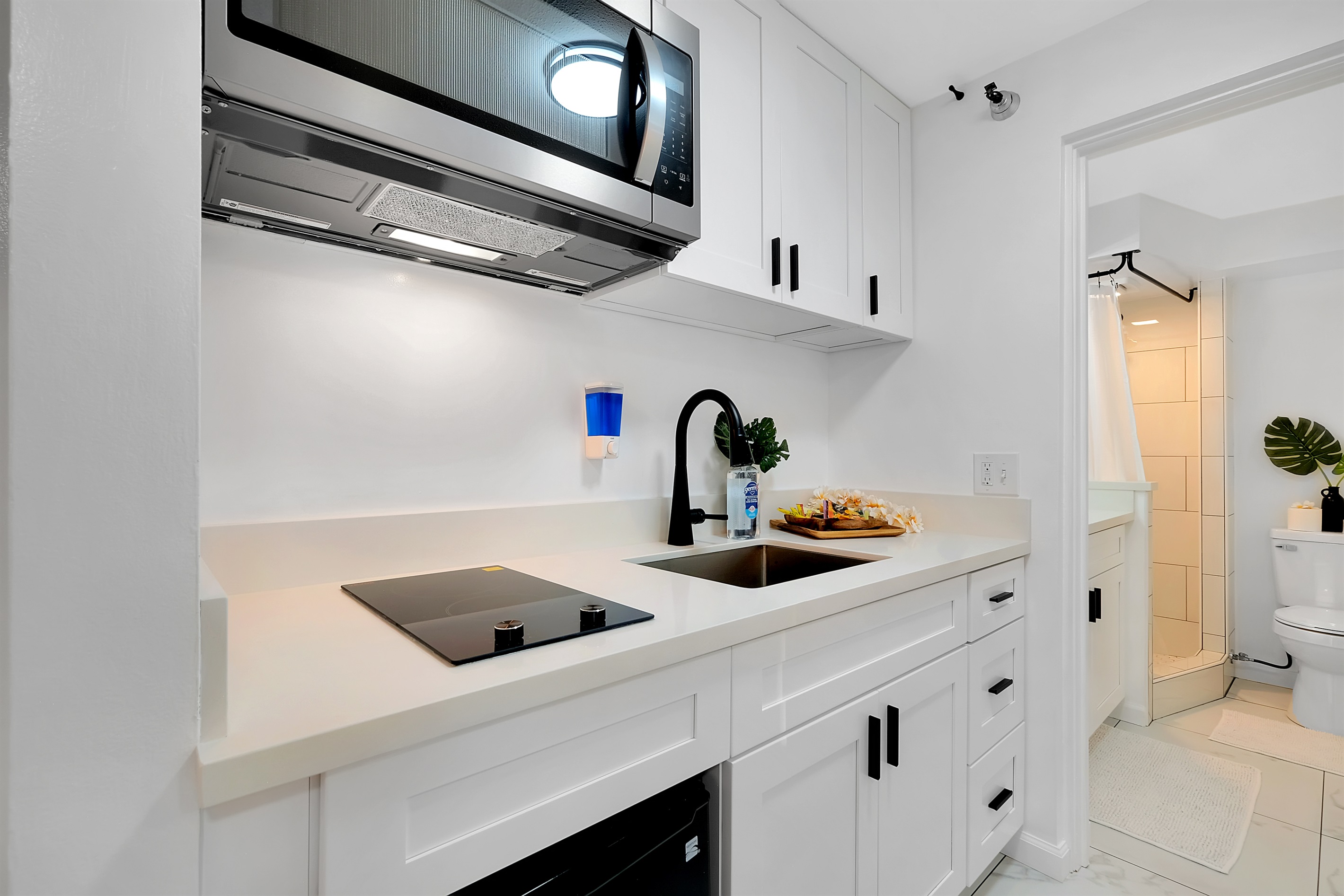 Your modern Waikīkī escape begins here — a bright, fully equipped kitchenette featuring sleek countertops, soft lighting, and easy access to the bathroom for total convenience. Designed for guests who appreciate comfort, function, and island elegance.