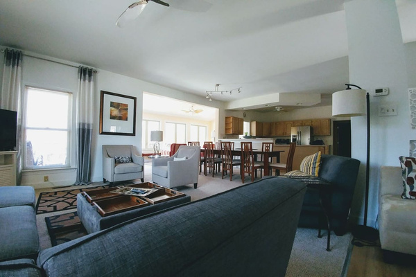 Looking from sectional towards large dining table, kitchen, sunroom and deck.