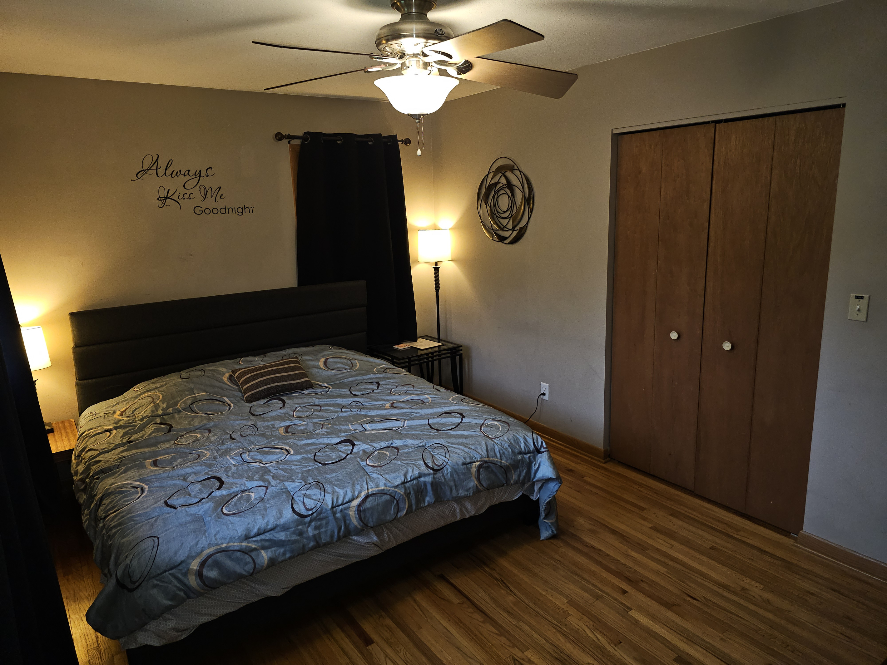 Master bedroom on the main floor with king bed, ceiling fan, alarm clock and a smart tv.