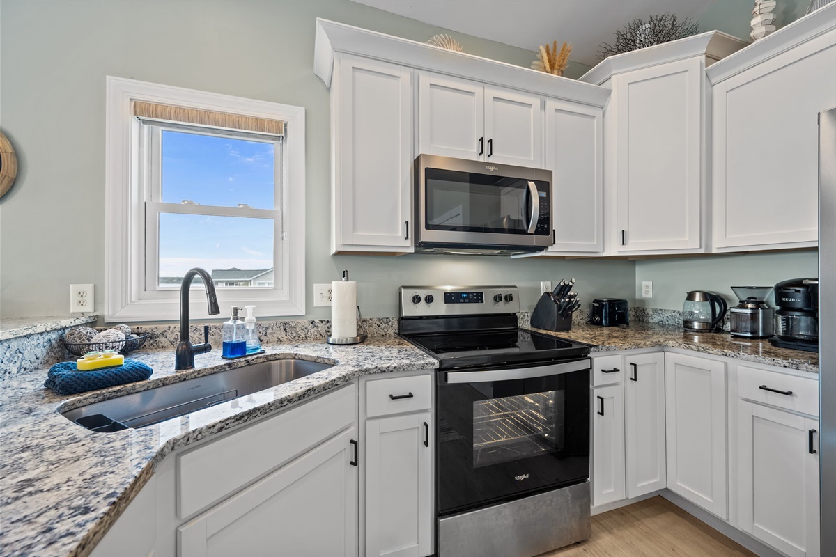 Fully stocked kitchen with all cooking essentials and sunshine through the window