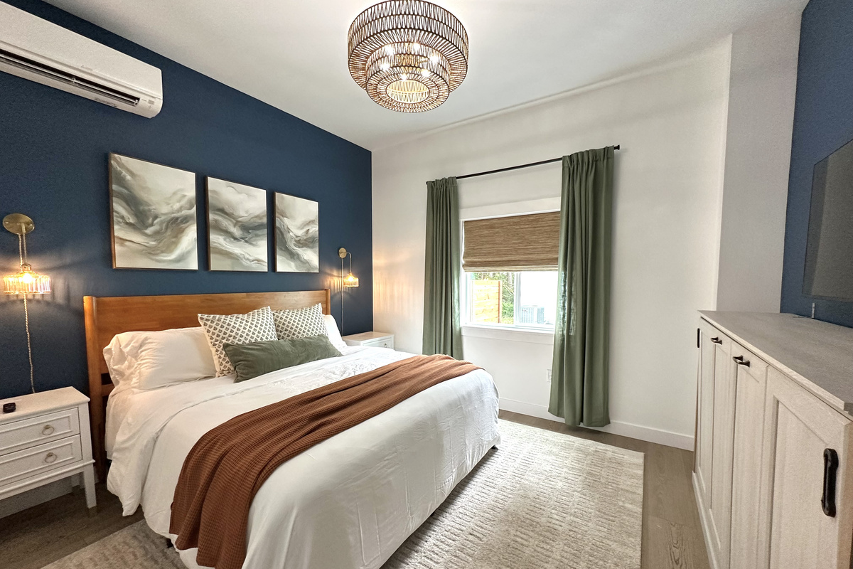 The primary suite: a king bed, moody navy accent wall, soft layered bedding and room to actually unpack.