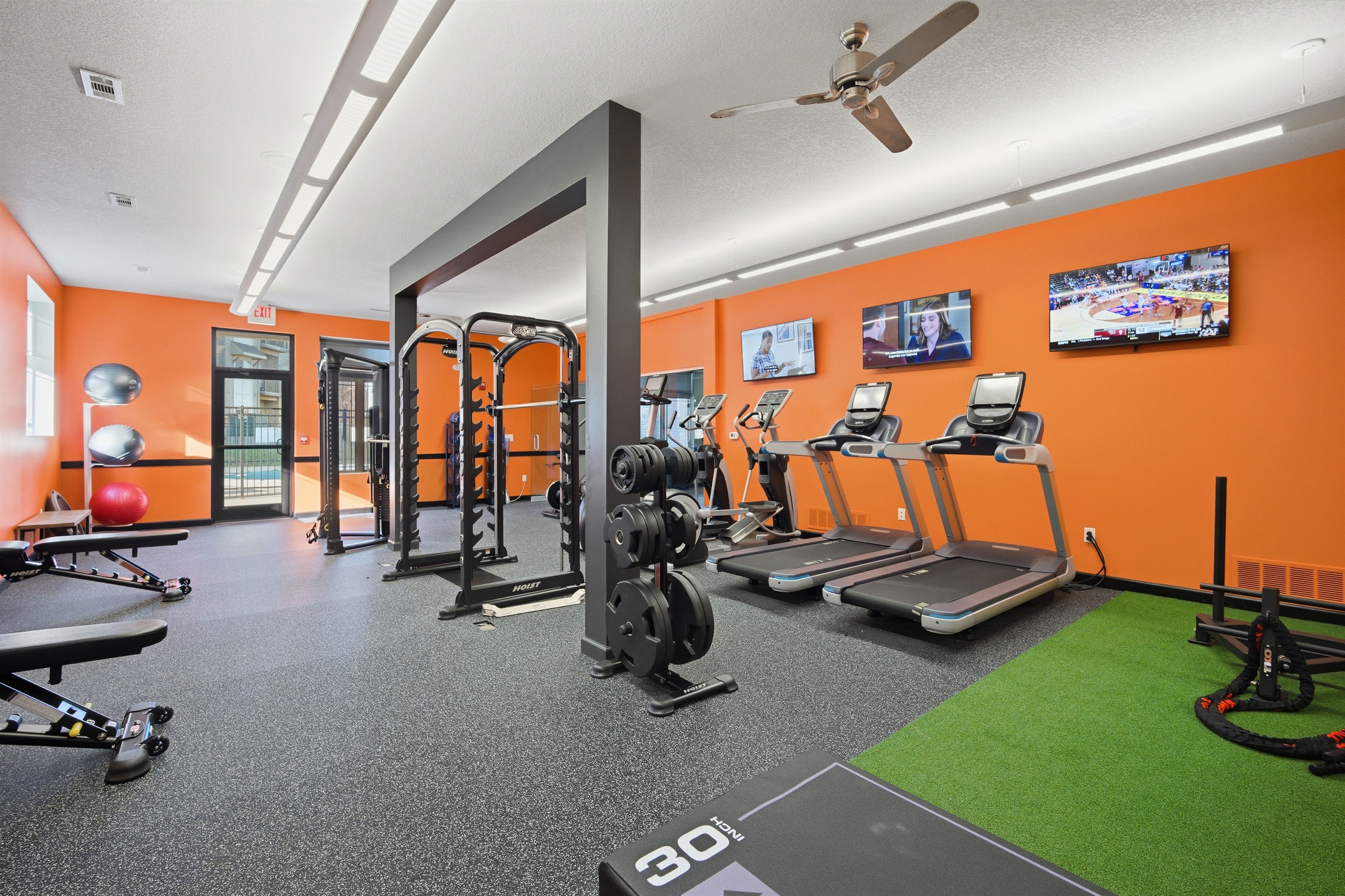Enjoy a focused cardio session with multiple treadmills and ellipticals, each positioned near wall-mounted TVs for entertainment.