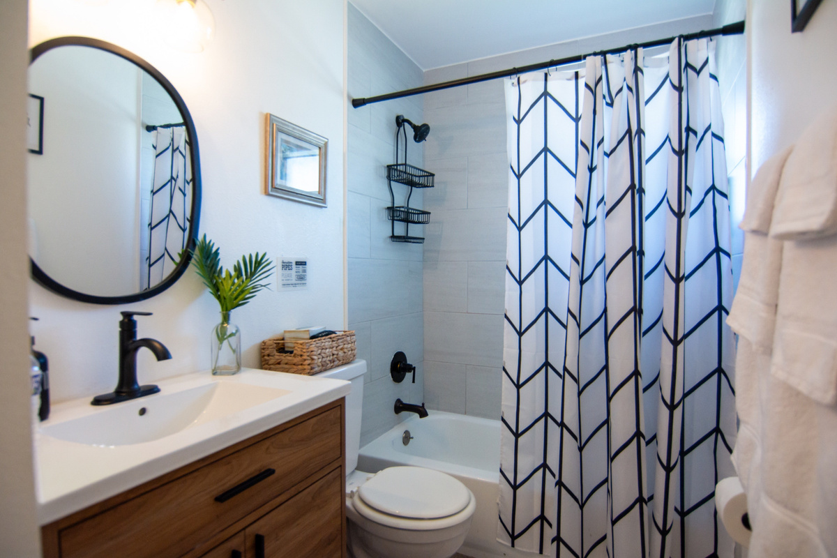 Palm House 2BR – Bathroom with tub/shower combo, modern vanity and hotel-style toiletries