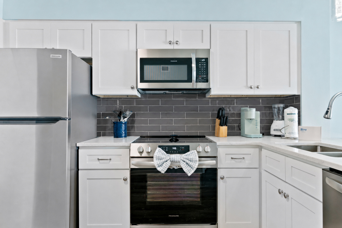 A modern kitchen featuring a sleek silver fridge, countertop stove with oven,dishwasher, microwave, and state-of-the-art appliances—fully equipped with everything you need for effortless cooking and dining.