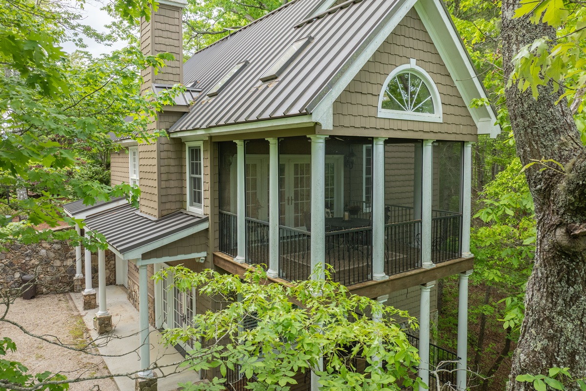 Cheoah Cottage features striking architecture, a metal roof, and a beautiful screened porch nestled among the trees.