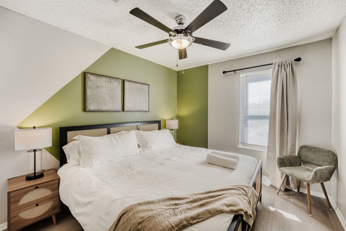 Cozy bedroom with modern decor, green accent wall, and warm natural light.