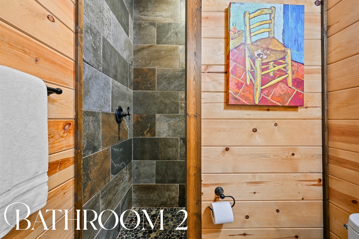 Bathroom 2 features slate tile, wood paneling, and rustic-modern charm in a bright, clean space.