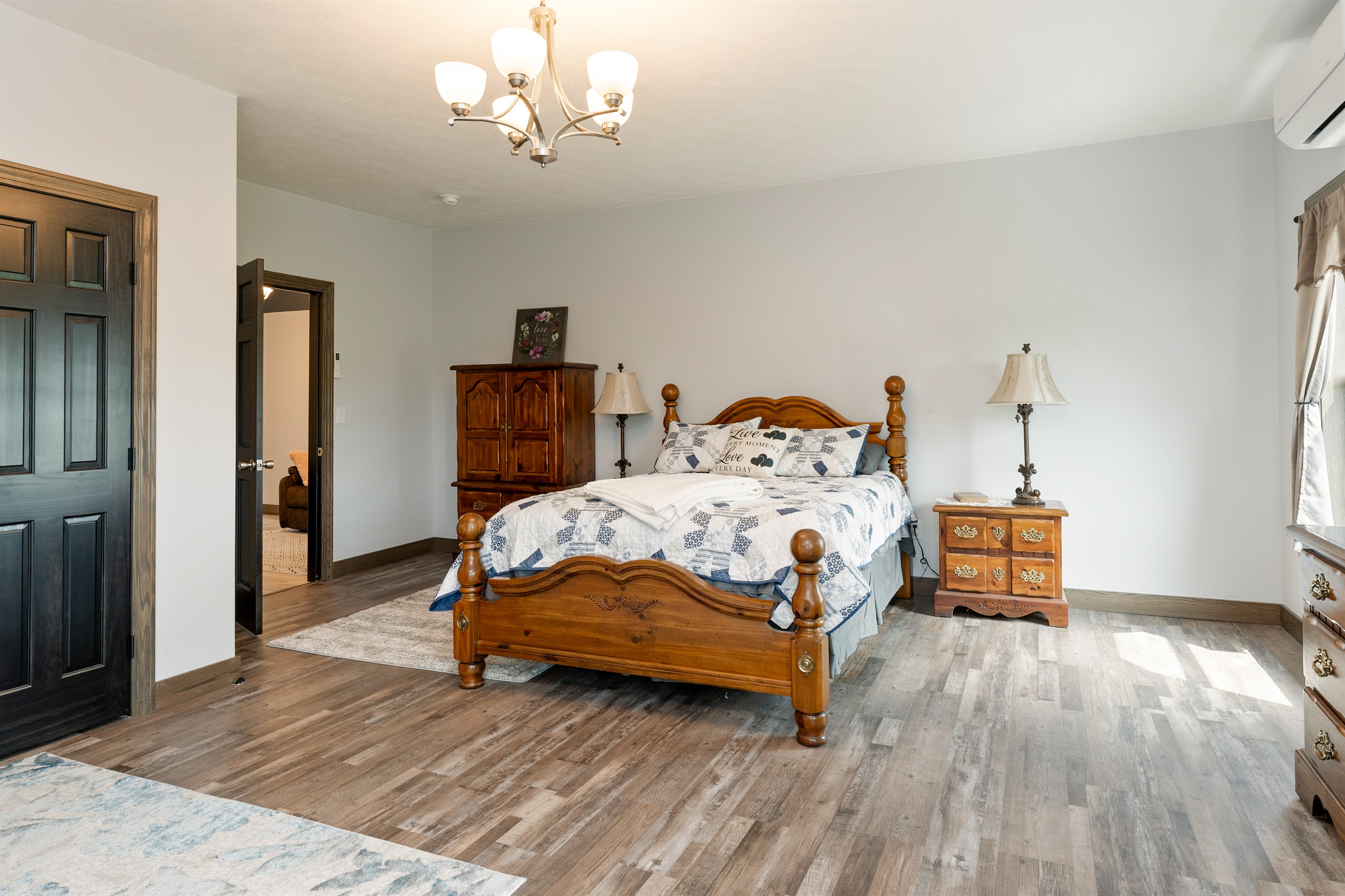 A bright and spacious master bedroom featuring a cozy queen bed, Queen fold out sofa and crib with elegant wood furniture, and stunning countryside views through large windows. Perfect blend of comfort and charm for a restful stay. Bedroom #1
