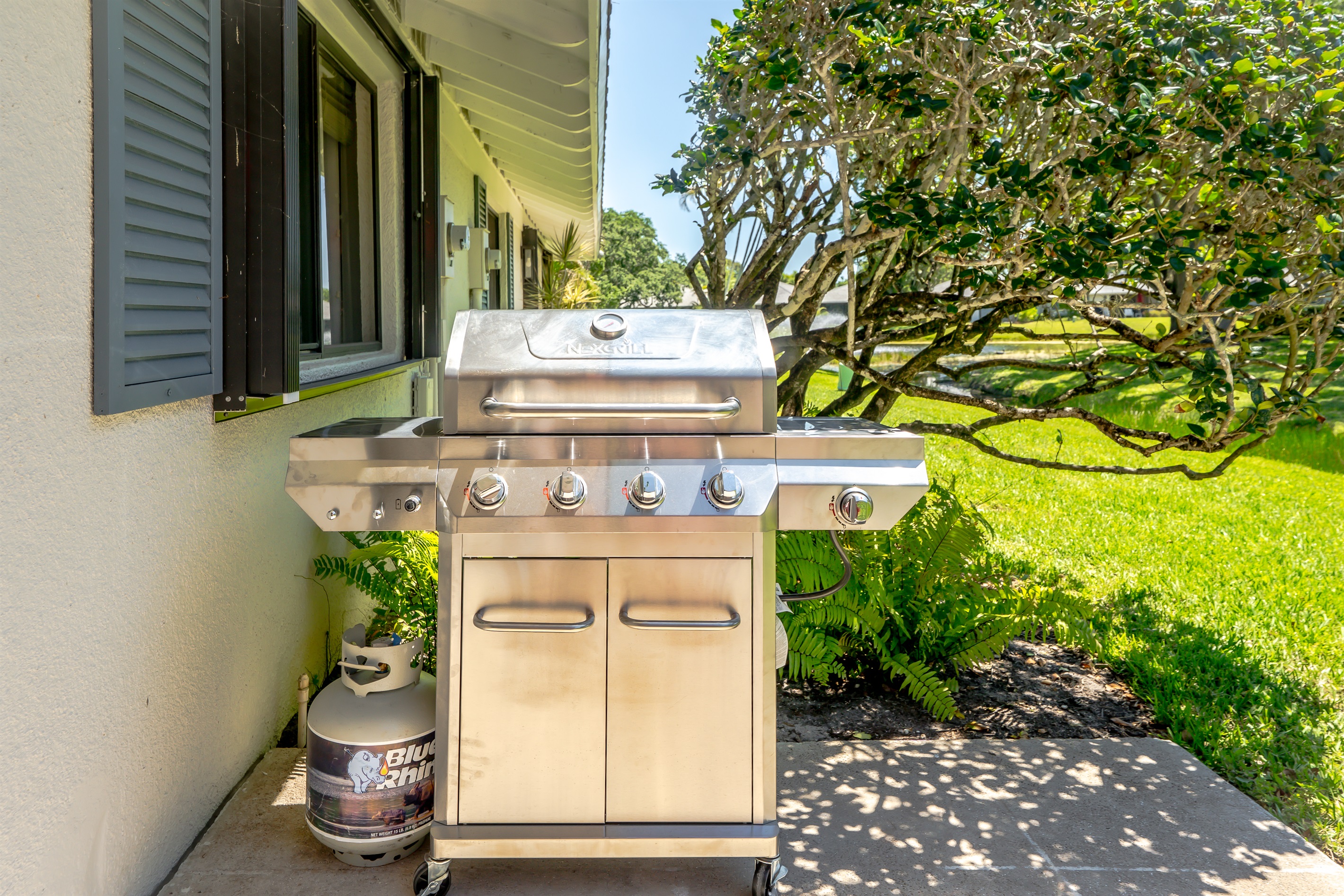 Private lakeside patio with outdoor dining, umbrella, and grill—perfect for morning coffee or sunset meals by the water
