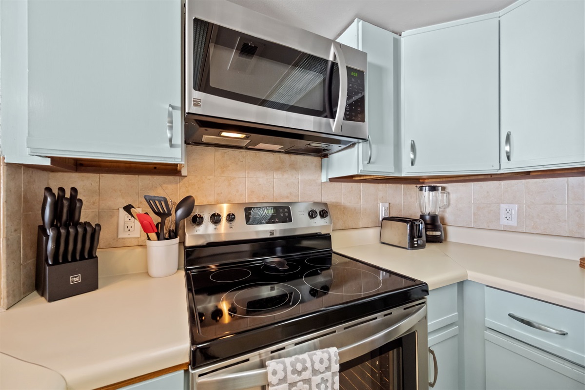Fully equipped kitchen featuring stainless steel appliances, electric range, microwave, and essential cookware for easy meal prep