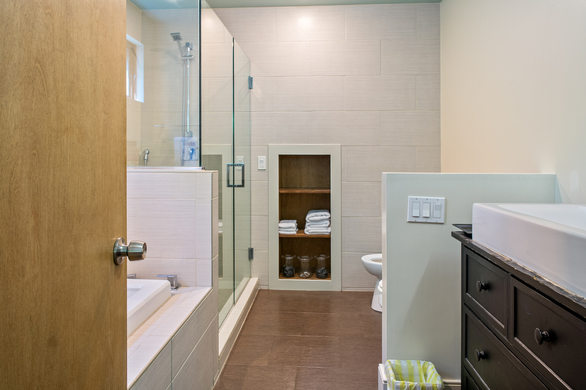 Spa-inspired relaxation at "The Crag." The primary en-suite bathroom features a glass-enclosed walk-in shower, a deep soaking tub, modern vessel sink vanity, built-in towel alcove, and elegant neutral tile throughout.