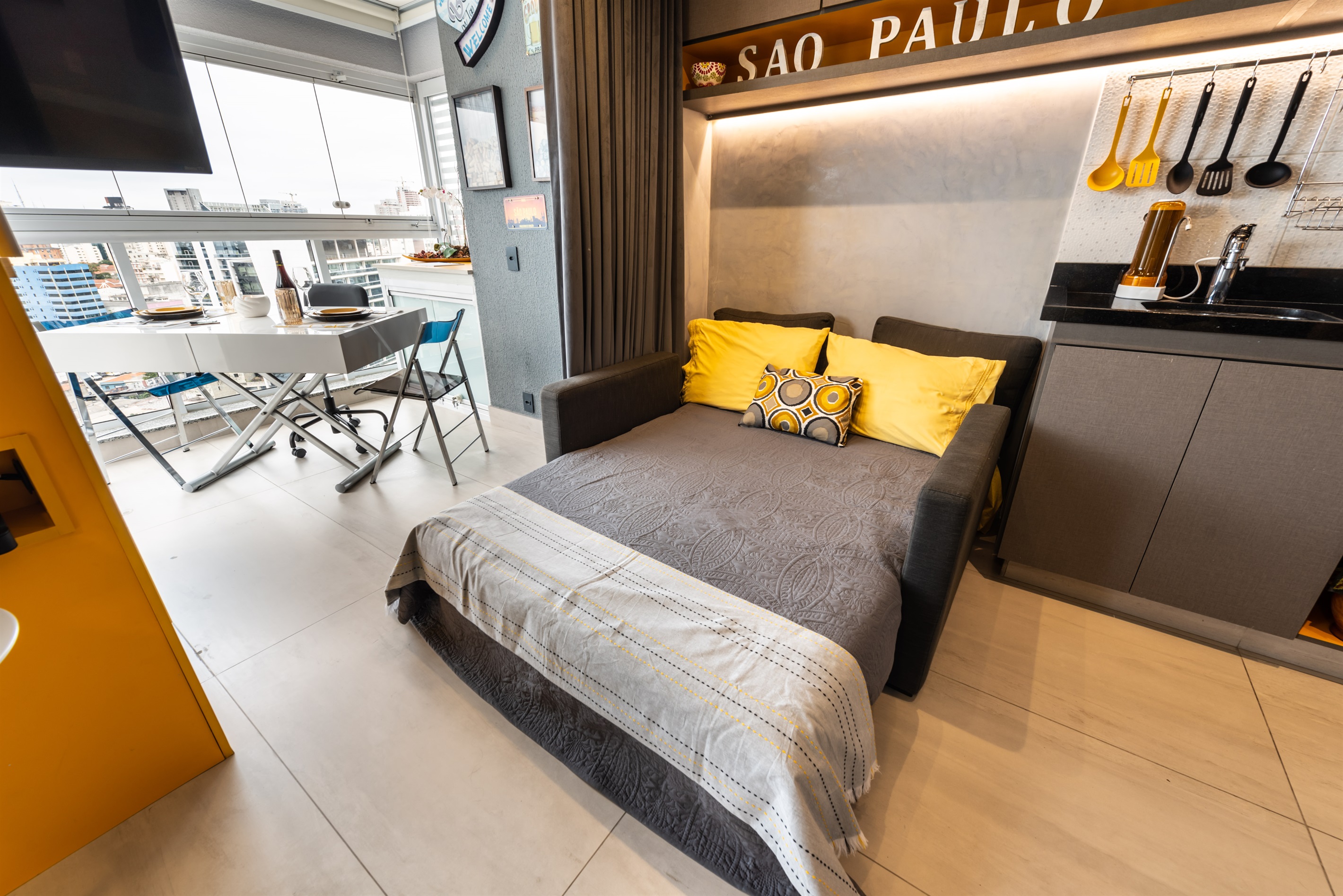 Sala de estar versátil com sofá-cama e vista para a varanda, combinando conforto e praticidade