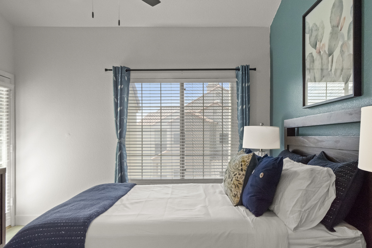 Bright and comfortable bedroom with a cozy bed, window blinds, and a peaceful setting for a relaxing vacation.