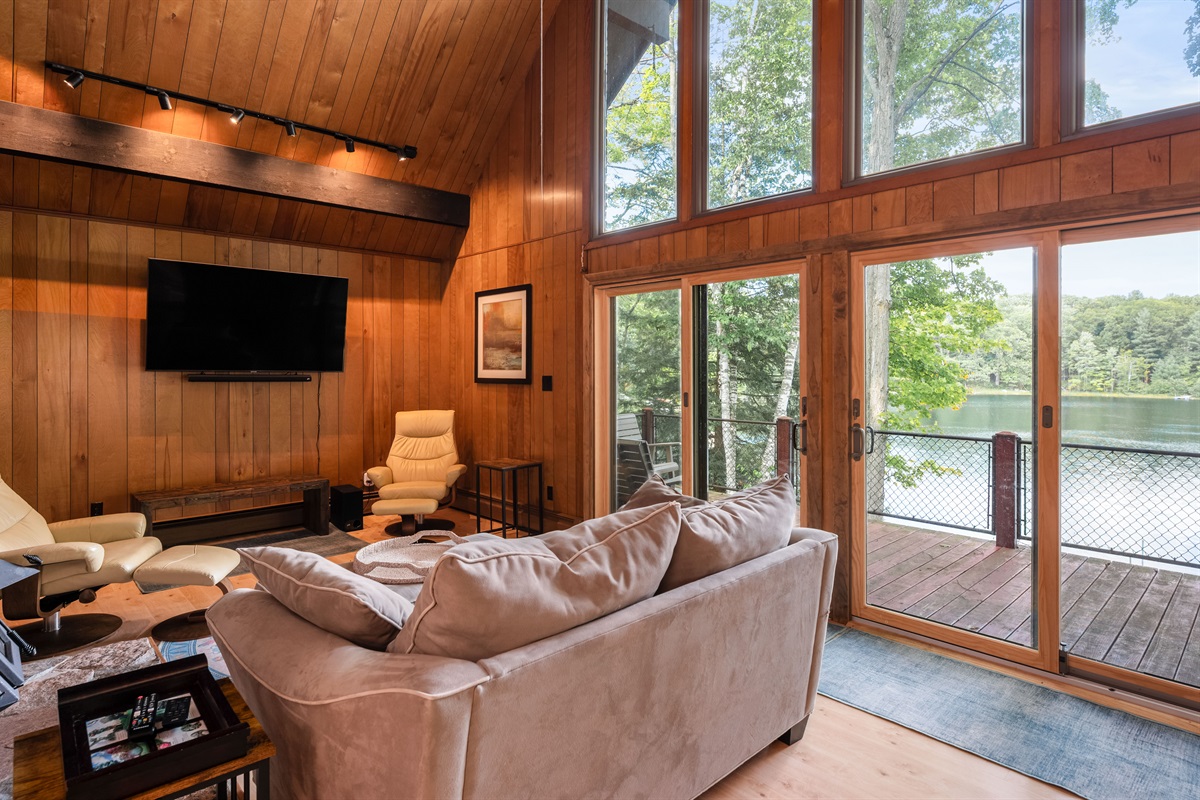 Main living area with vaulted ceilings, large windows, and lake views