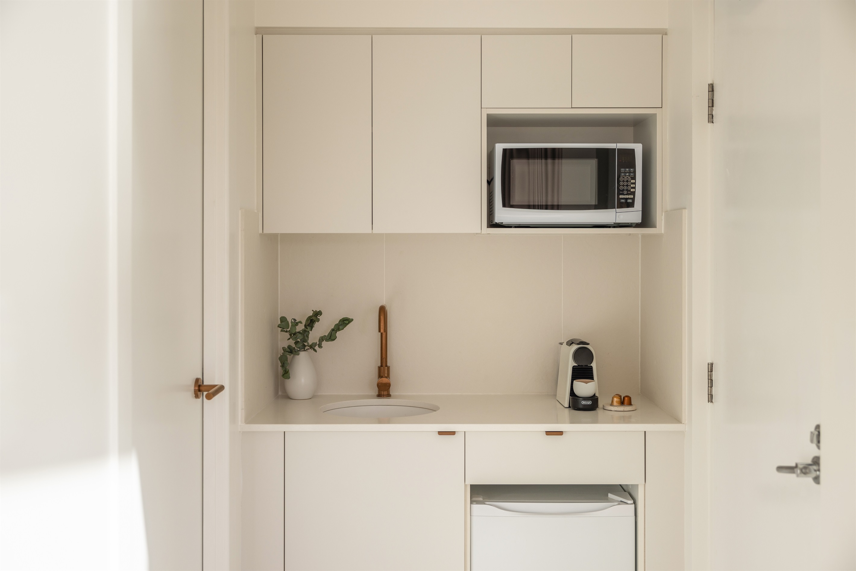 Stylish studio kitchenette with premium brushed-copper tapware and Nespresso coffee station.