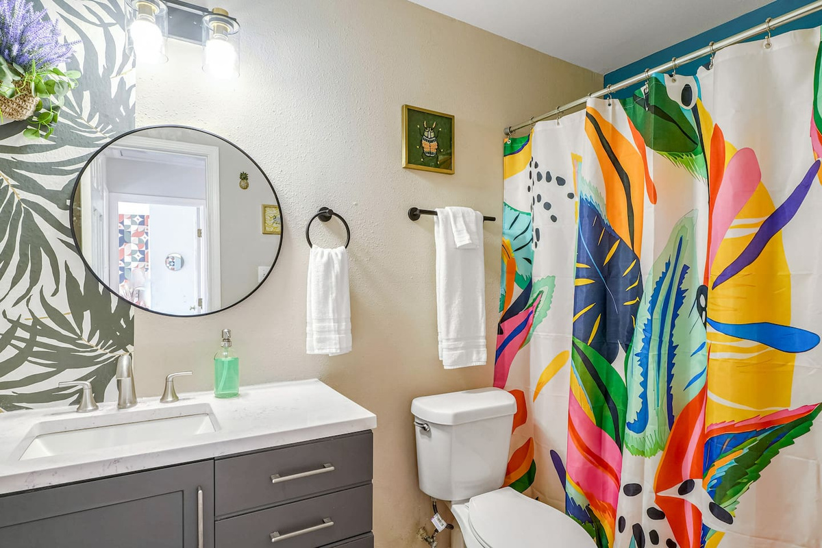 Your downstairs full bathroom is accessible to all and boasts leafy wallpaper and modern accents
