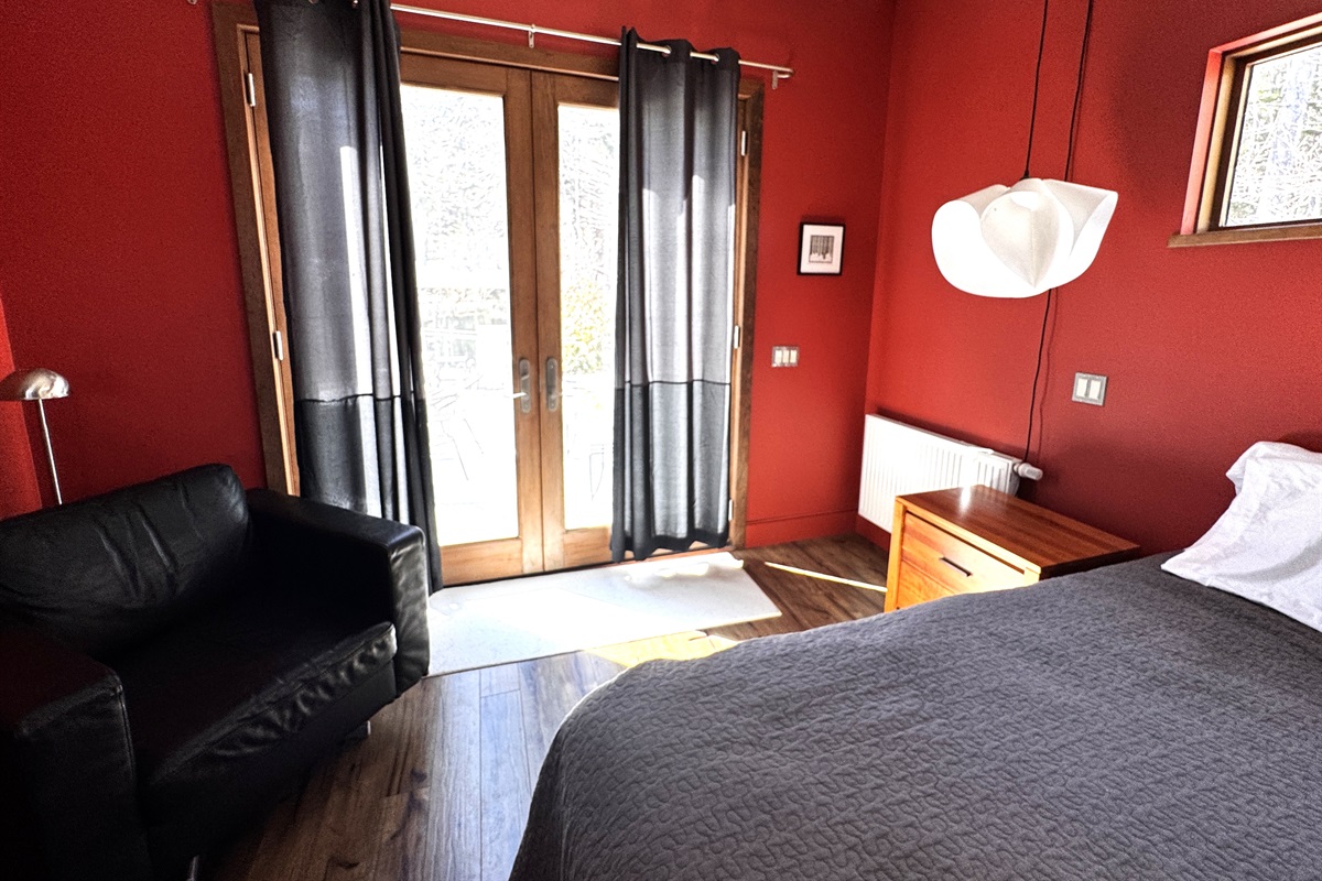 The primary suite features a cozy leather armchair and direct access to the 33ft deck through oversized French doors. This seamless indoor-outdoor flow allows you to enjoy the fresh Acadia air and the sounds of the forest right from your bedroom.