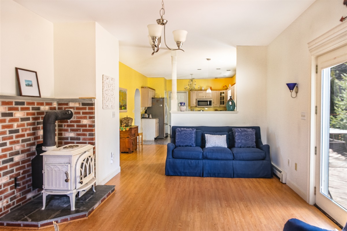 Relax in the main living room, offering plenty of seating and a seamless view into the kitchen. While the antique stove is decorative only, the bright space and French doors to the deck provide the perfect atmosphere for your Acadia National Park stay.