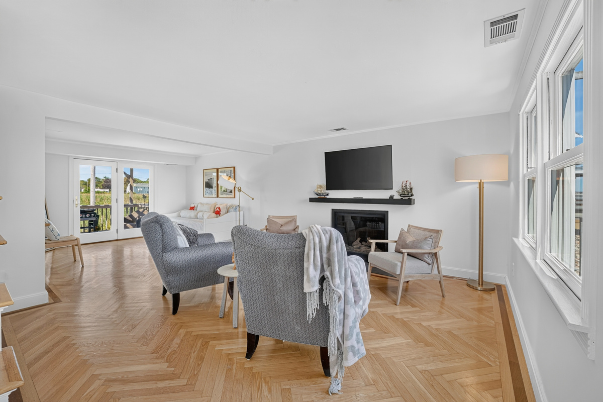 Light-filled living room with panoramic water views, cozy seating, and direct access to the outdoor deck.