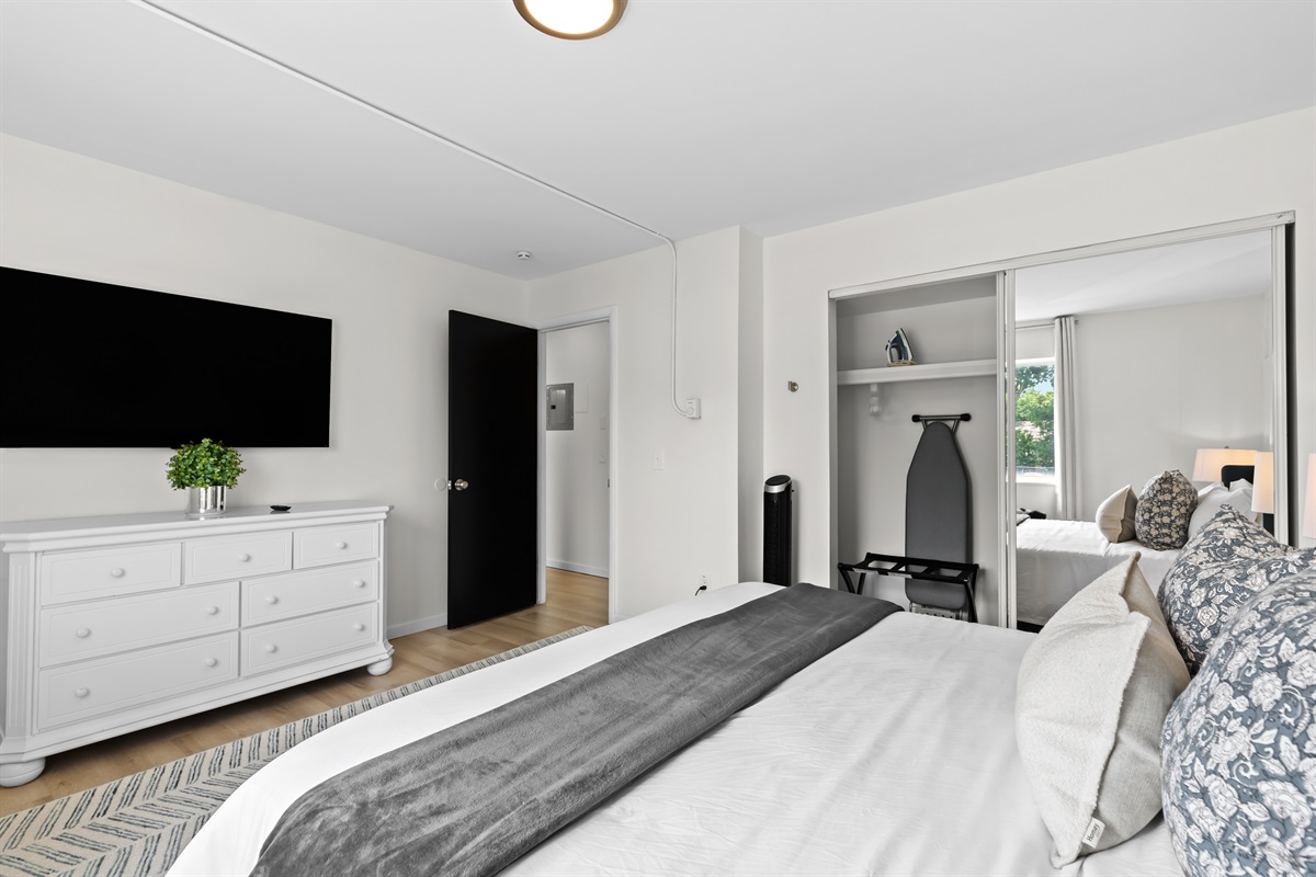Comfortable bedroom with wall-mounted TV and direct living room access.