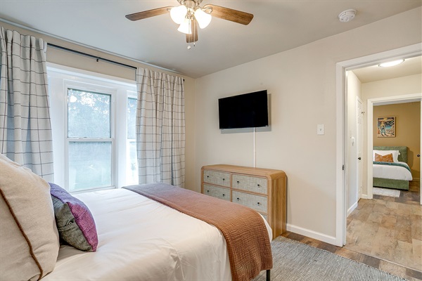 Queen bedroom with blackout curtains, dresser, and smart TV—perfect for cozy nights in
