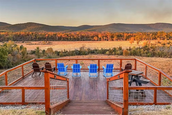 Expansive elevated deck with Adirondack seating and panoramic mountain and river views.