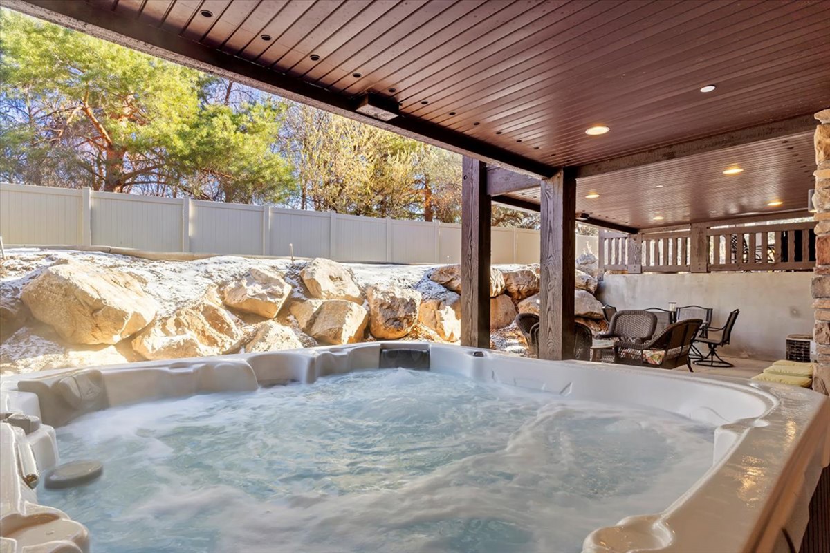 Unwind in your private hot tub beneath a covered patio, surrounded by natural stone and serene mountain views—your own spa-like retreat.