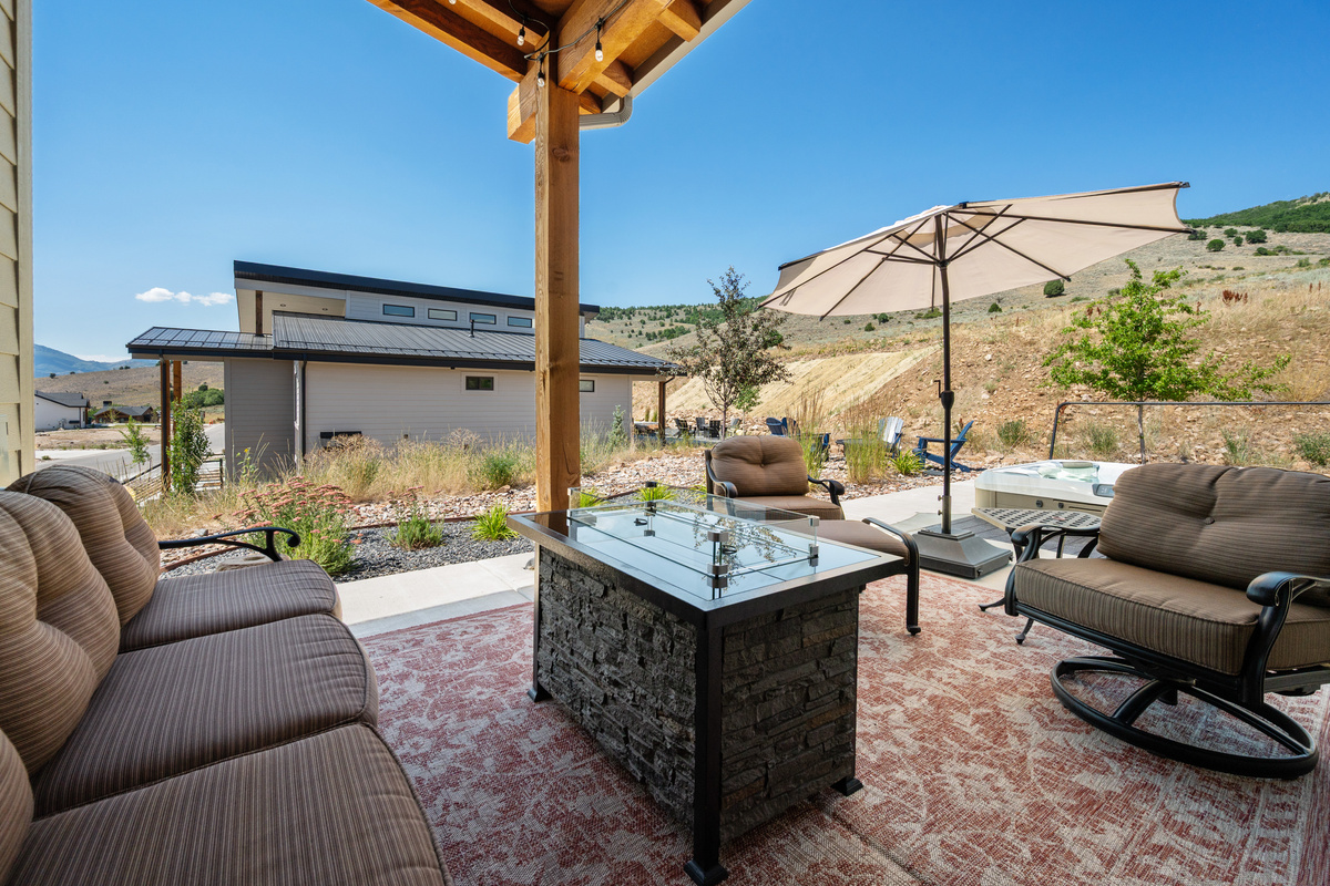 The spacious patio offers the perfect place to unwind with a fire table, private hot tub, and beautiful mountain surroundings.