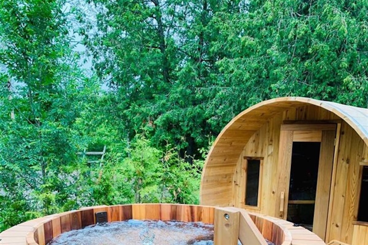 Private barrel sauna and hot tub surrounded by forest