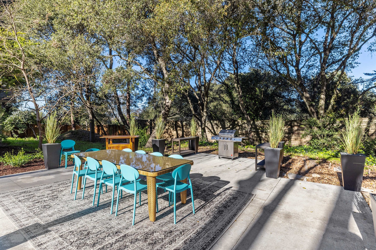 The dining pavilion hosts a large dining table with seating for 12, a grill, an outdoor bar, and serving area. It is adjacent to the bocce court, pool,  and the front door to the home.