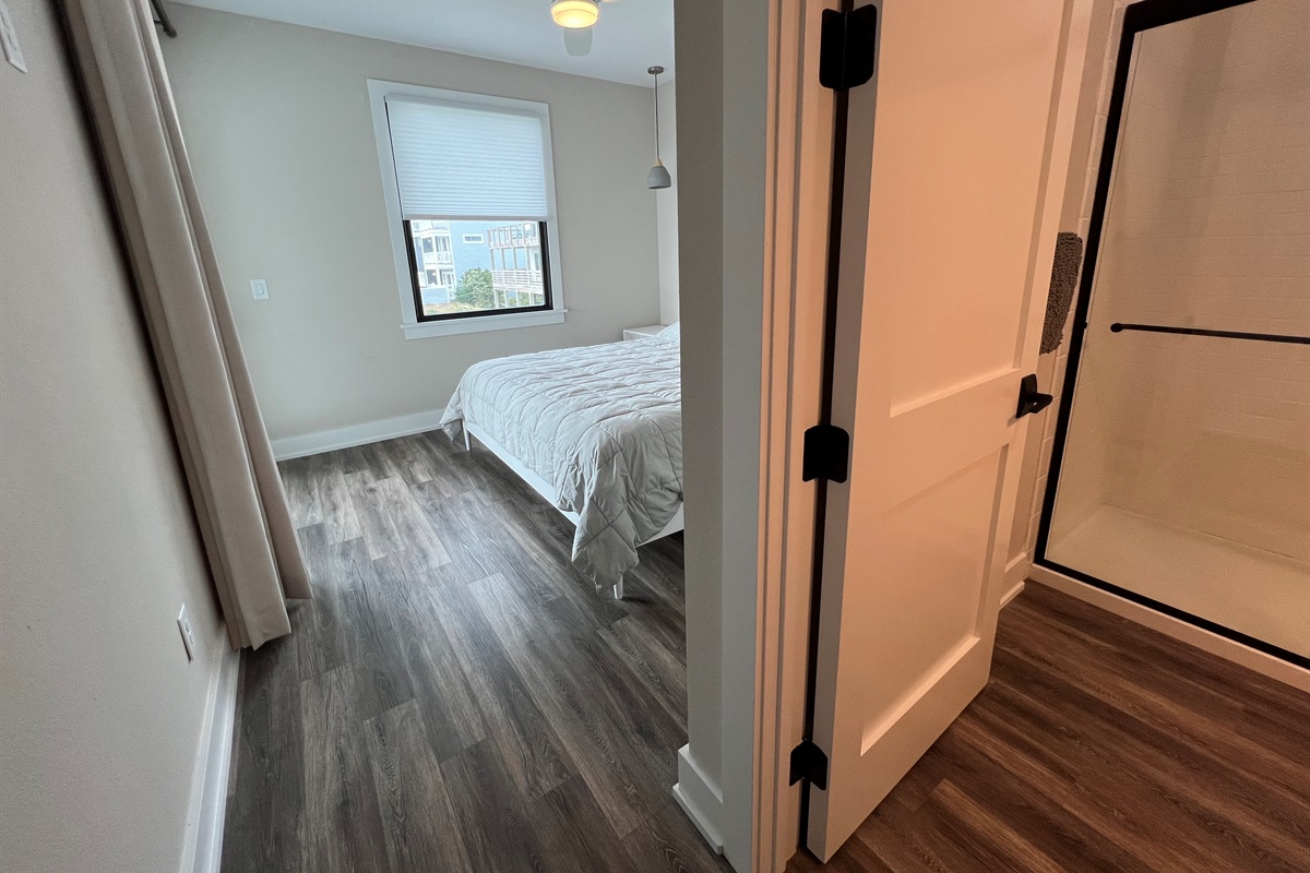 North King bedroom with ensuite and door to deck with hot tub.