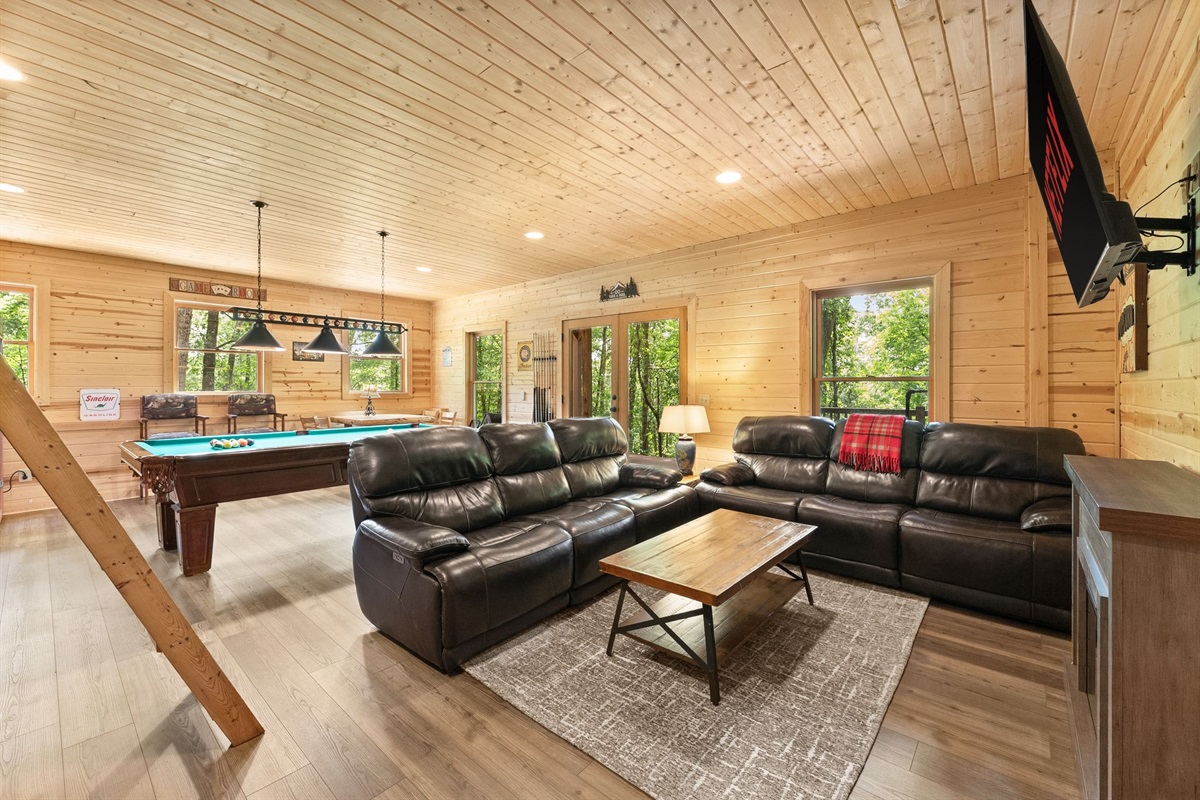 Lower-level entertainment room featuring comfortable lounge seating, a TV, and pool table for the perfect cabin game night.