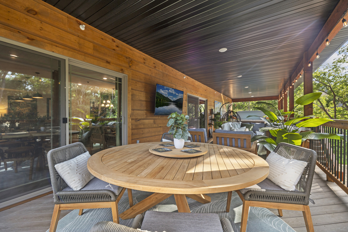 A round teak table for open-air meals under the covered deck.