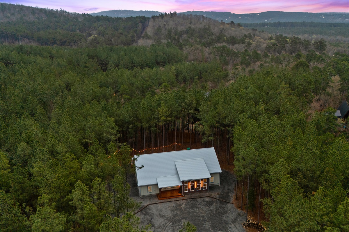 An aerial view reveals the peaceful forest setting surrounding the cabin, highlighting the privacy and natural beauty of the property.