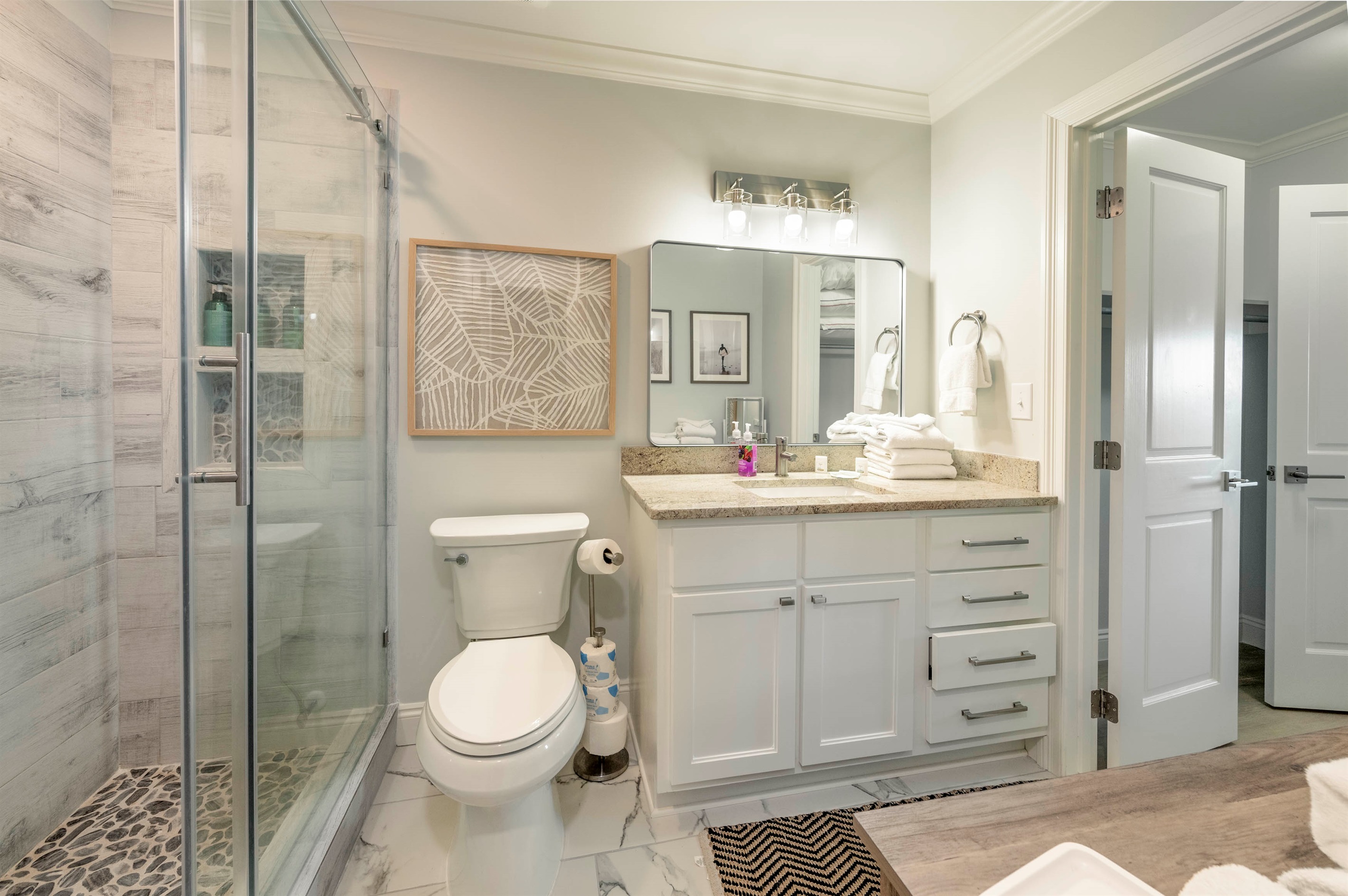 Elegant modern bathroom with stylish decor, glass shower, granite countertop, and soft lighting.