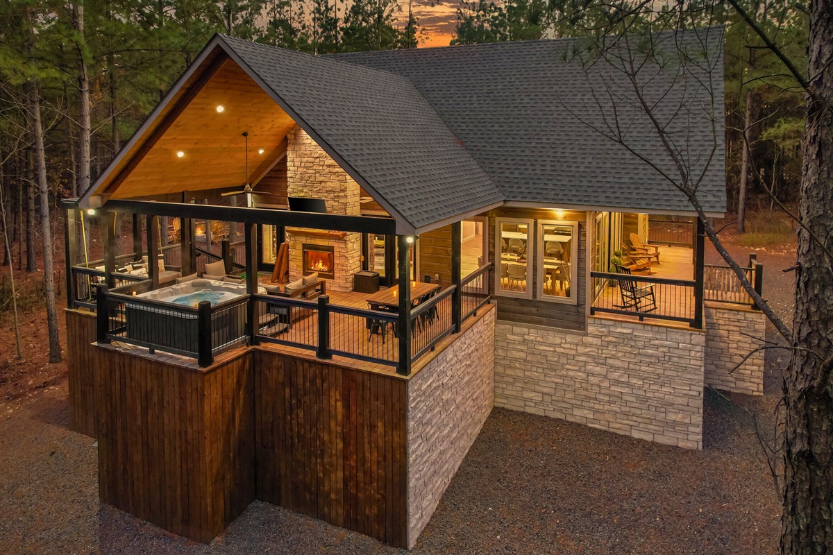 Night view of cabin exterior with glowing windows and deck.