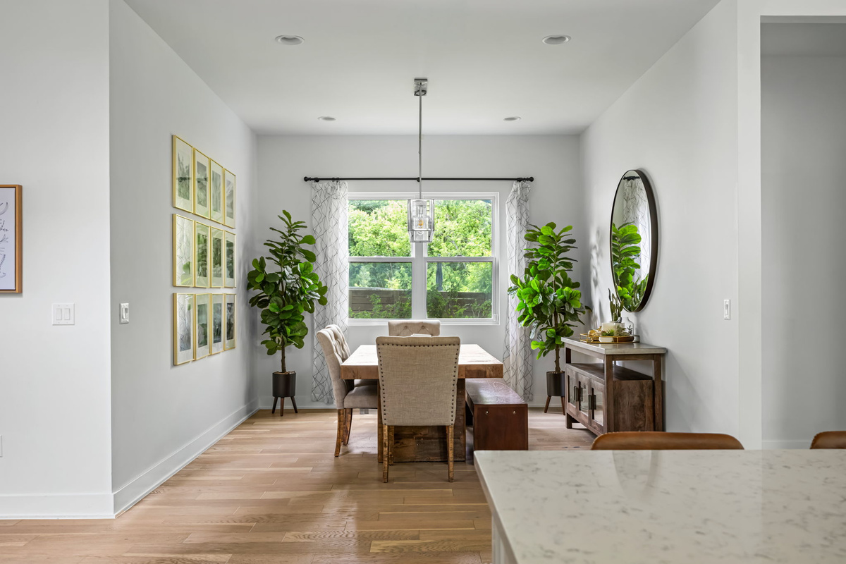 Elegant dining area with a wooden farmhouse table, gallery wall, and abundant natural light — an inviting space for shared meals and conversation.