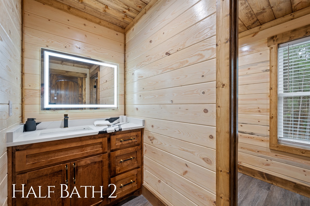 The half bathroom near the bunkroom includes a bright vanity and modern lighting, creating a convenient space for guests to freshen up.