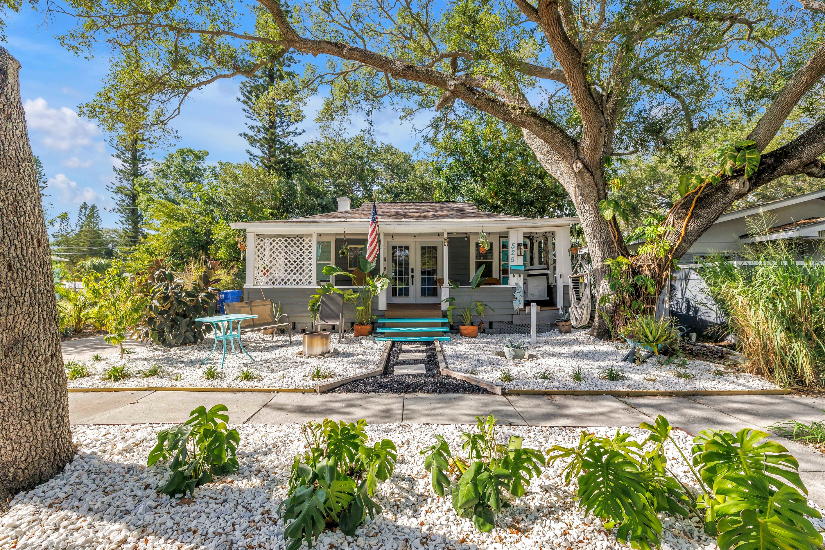 Charming exterior with a welcoming front porch, landscaped yard, outdoor seating, and a peaceful garden-style setting.